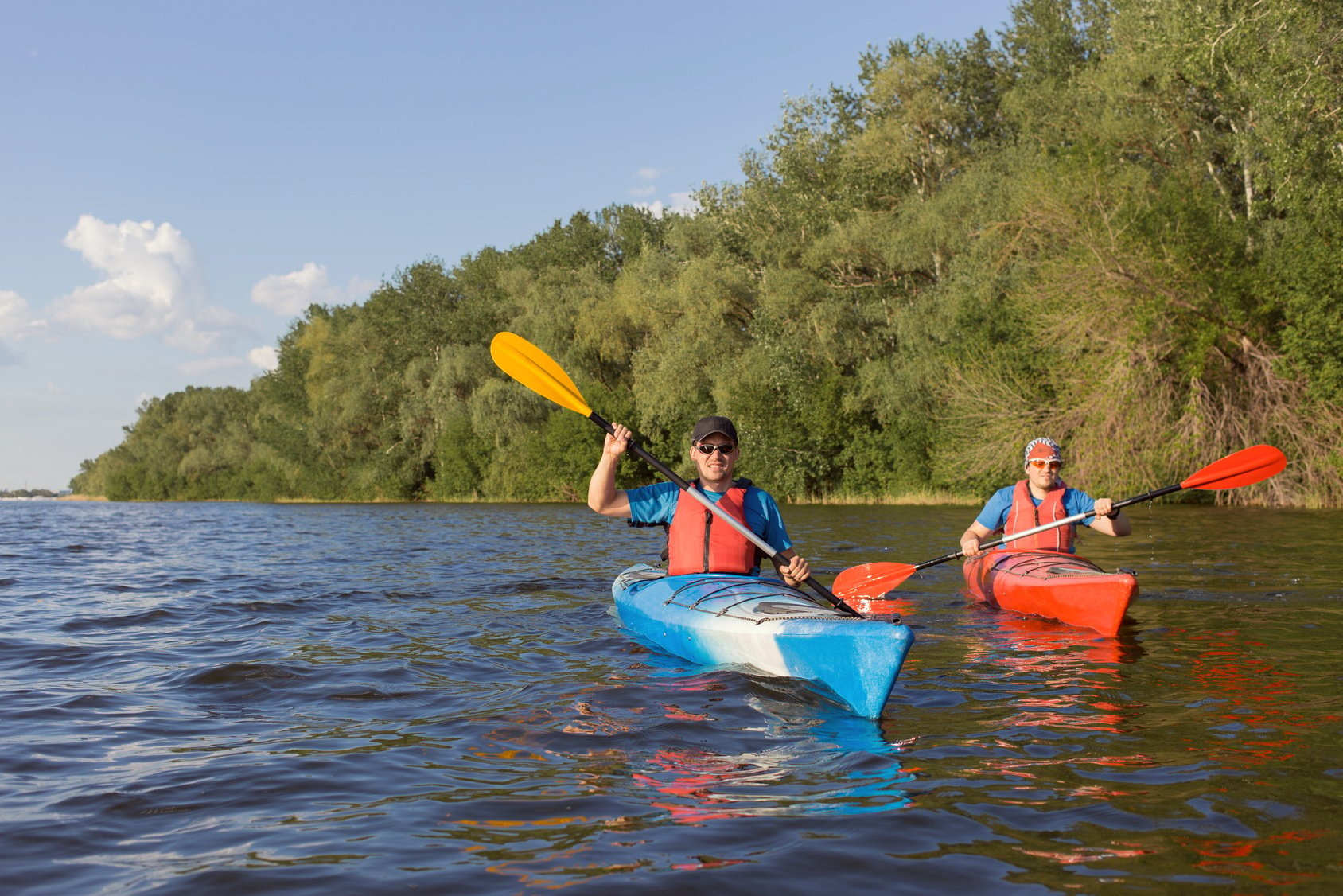 Two guys travel the river on a kayaking in the summer.