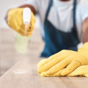 Ammattisiivooja puhdistaa kodin pöytäpintaa kotisiivouksen yhteydessä pääkaupunkiseudulla